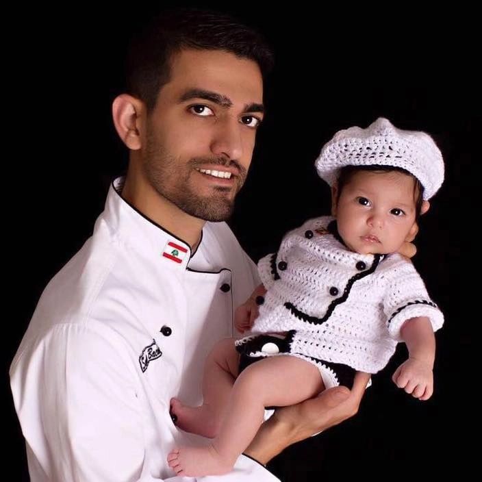 The founder of Lara’s Cakes in his chef jacket, holding his daughter